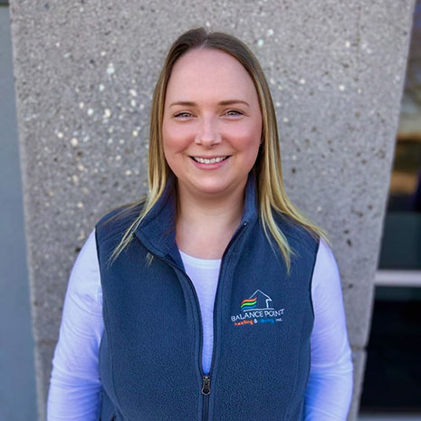 Brooke wearing a Balance Point vest standing in front of a gray building